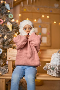 Portrait of young woman standing against christmas tree
