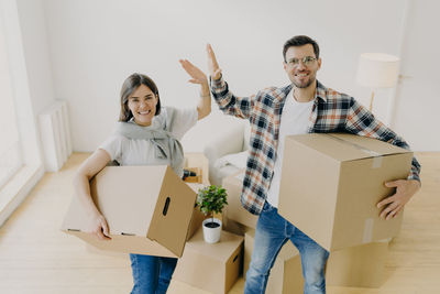 Portrait of smiling couple carrying boxes giving high five at home