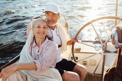 Portrait of smiling senior woman with husband sailing in sea