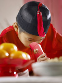 Close-up of teenage boy in traditional clothes looking in envelope