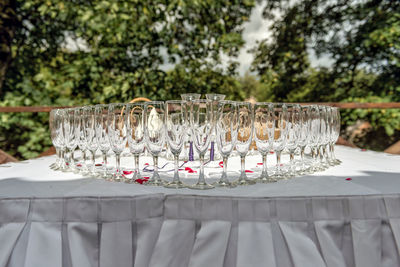 Close-up of glasses arranged on table against trees