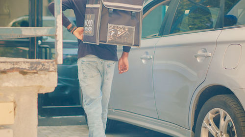 Midsection of man standing in car