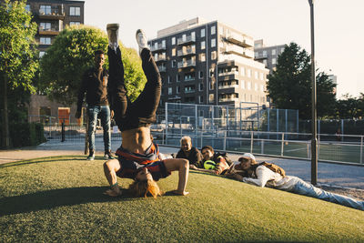 People relaxing on grassland against buildings in city