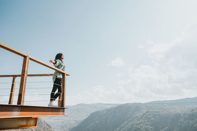 Rear view of woman standing on mountain against clear sky