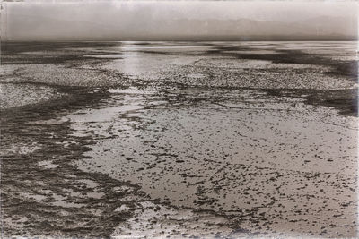 Wet sand on beach against sky