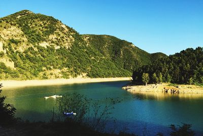 Scenic view of river and mountains against clear blue sky