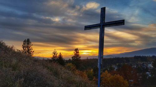 Cross on field against sky during sunset