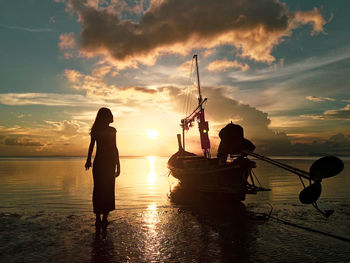 Silhouette woman on beach against sky during sunset