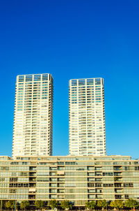 Low angle view of modern buildings against clear blue sky