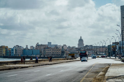 View of city street against cloudy sky