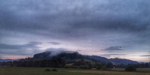 Scenic view of field against storm clouds