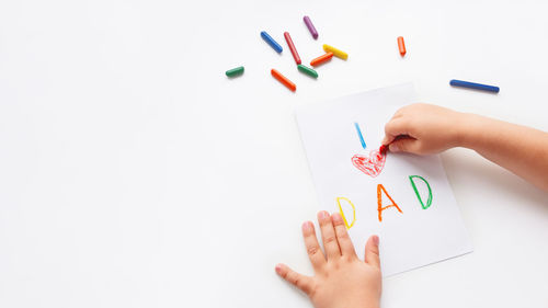 Cropped hand of woman holding paper against white background