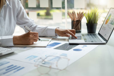 Midsection of business people working on table