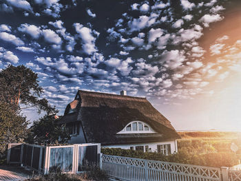 House and trees on field against sky