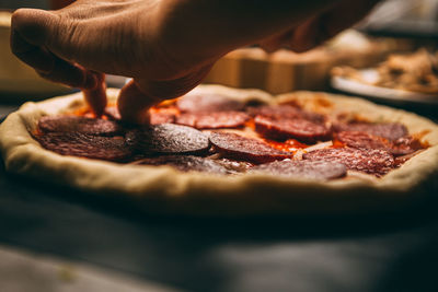 Closeup hand of chef baker in white uniform making pizza at kitchen