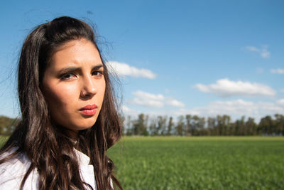 Portrait of young woman looking away against sky