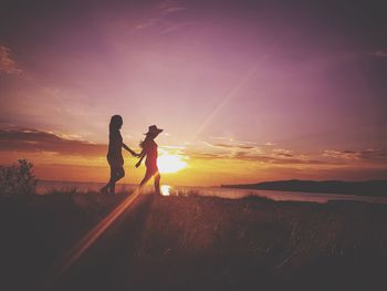 Friends walking on field against sky during sunset