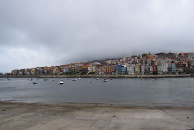 Scenic view of sea by buildings against sky