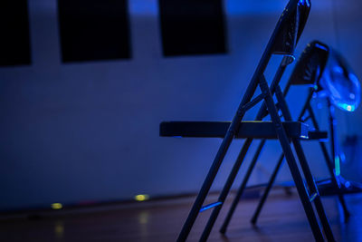 Low angle view of illuminated lighting equipment on table against wall