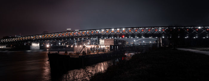 Illuminated bridge over river at night