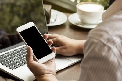 Midsection of man using mobile phone on table