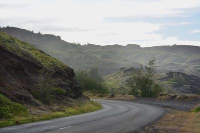 Road by mountains against sky
