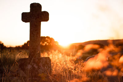 Cross on field against sky during sunset