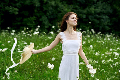 Portrait of smiling young woman standing against plants