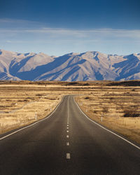 Road leading towards mountains against sky