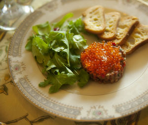 Close-up of steak tartare with rusk and arugula in plate