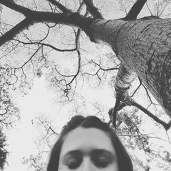Close-up portrait of young woman against bare tree