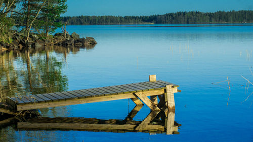 Pier on lake against blue sky