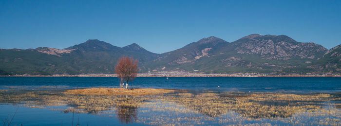 Scenic view of lake and mountains against clear blue sky