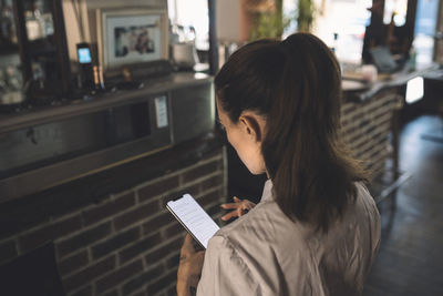 High angle view of female chef using smart phone in restaurant