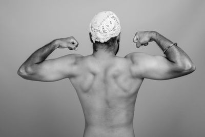 Midsection of shirtless man against gray background