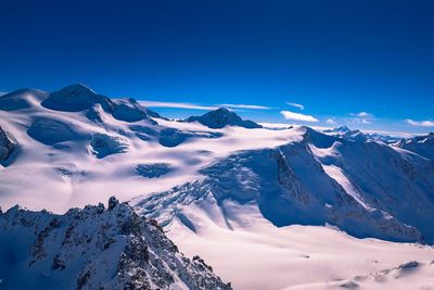 Scenic view of snowcapped mountains against blue sky