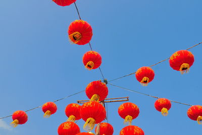 Low angle view of chinese lanterns hanging against clear blue sky