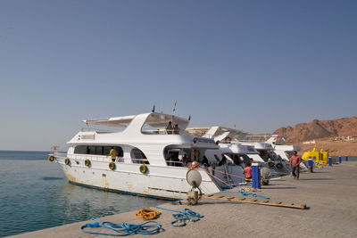 People on boat in sea against clear sky