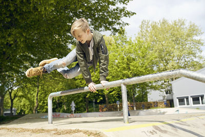 Boy jumping over railing in skatepark