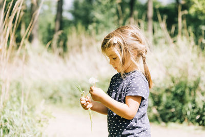 Cute girl holding flower standing outdoors