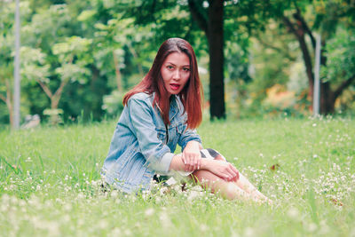 Portrait of young woman on grass in field