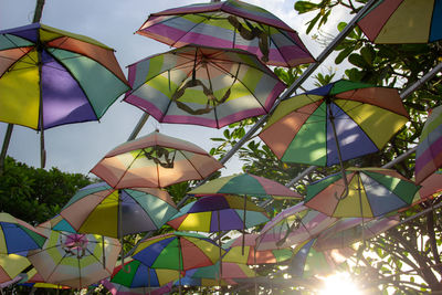 Low angle view of multi colored umbrellas hanging against sky