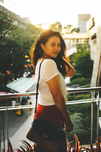 Portrait of woman standing against railing