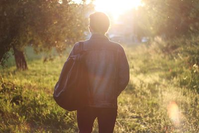 Rear view of man on grassy field during sunny day