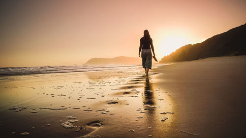 Full length rear view of a woman walking on beach