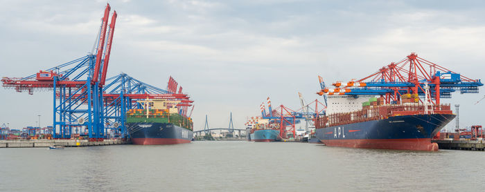 Cranes at commercial dock against sky