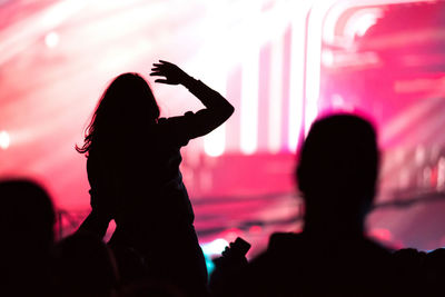 Rear view, silhouette of concert crowd. bright red stage lights in the background