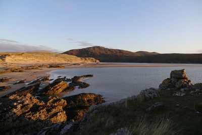 Scenic view of sea and mountains against clear sky