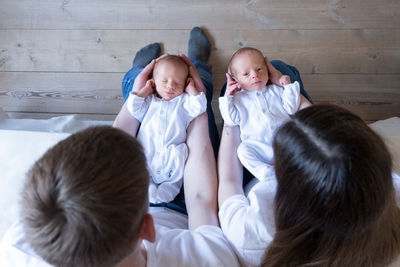 Newborn identical twins on the bed, on a parents hands. life style, emotions of kids. infant babies 