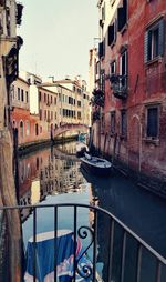 Boats moored in canal by city against sky